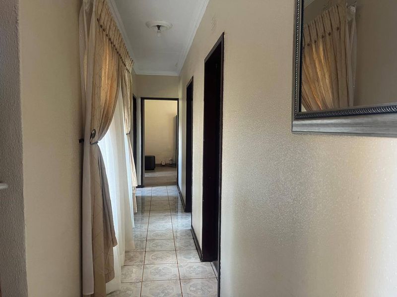A functional hallway featuring tiled flooring, neutral walls, and access to multiple rooms, providing a clean and simple transition space.