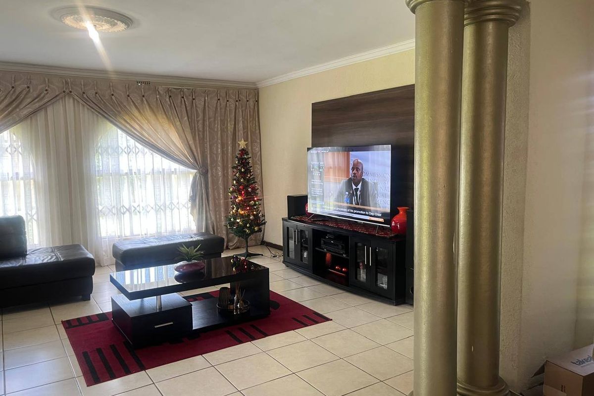 A spacious living room featuring tiled flooring, decorative columns, and a ceiling rose, providing a comfortable and functional area for relaxation.