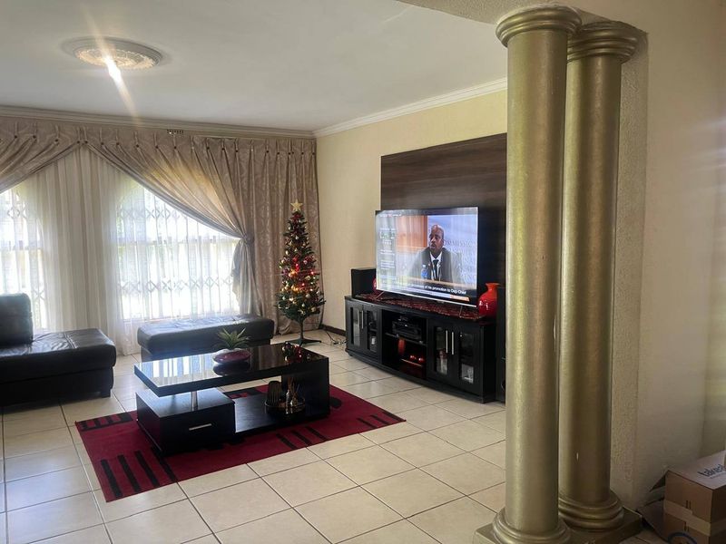 A spacious living room featuring tiled flooring, decorative columns, and a ceiling rose, providing a comfortable and functional area for relaxation.