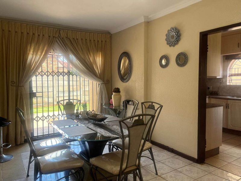 Dining area featuring tiled flooring and a sliding door with security gate, providing access to the exterior.