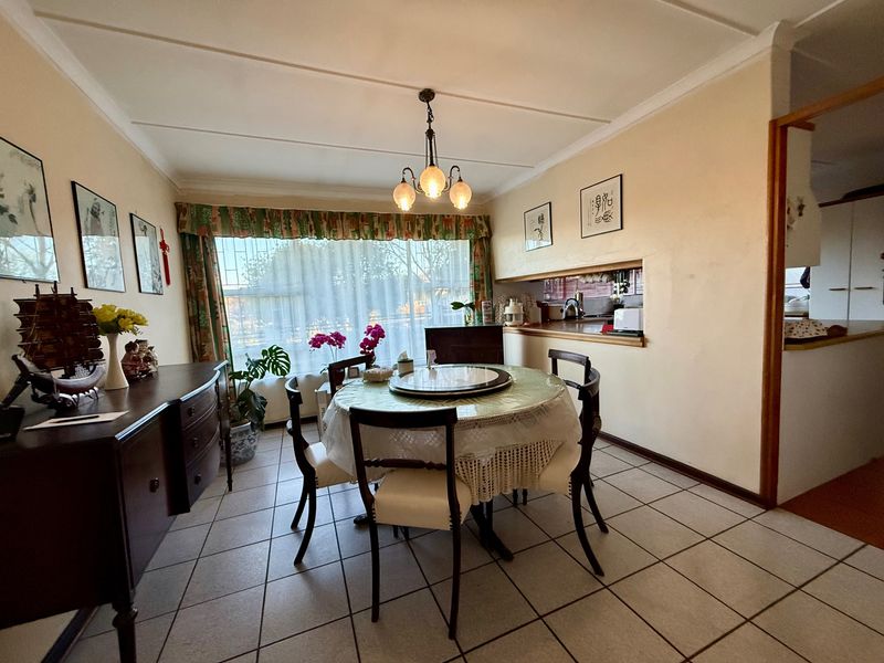 A dining room featuring tiled flooring, a central light fixture, and a convenient pass-through window connecting to the kitchen area.