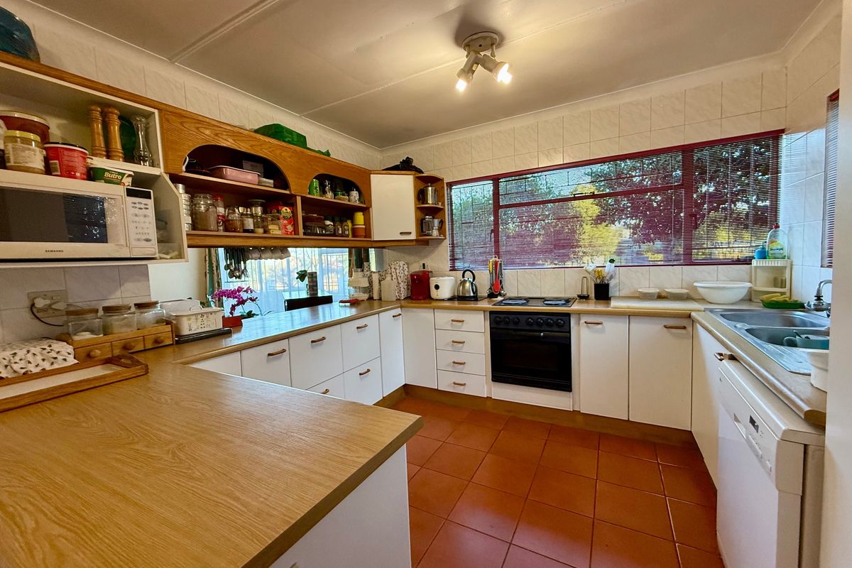 Functional kitchen featuring laminate countertops, ample built-in cabinetry, tiled backsplash, and a built-in oven with hob, offering a practical layout for daily cooking.