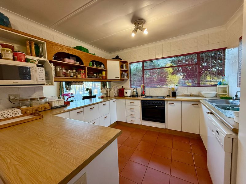 Functional kitchen featuring laminate countertops, ample built-in cabinetry, tiled backsplash, and a built-in oven with hob, offering a practical layout for daily cooking.