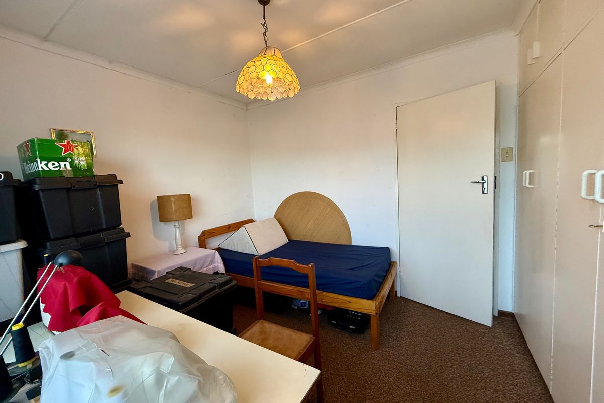A bedroom featuring built-in cupboards, carpeted flooring, and a central pendant light fixture, requiring cosmetic updates to improve its overall condition.