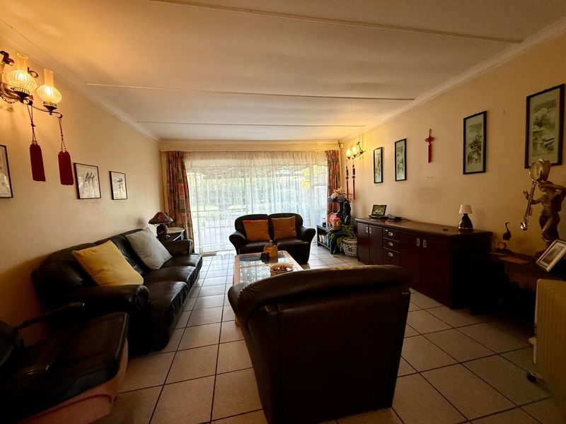 A spacious living room featuring tiled flooring and a large sliding glass door providing access to the outdoor area.