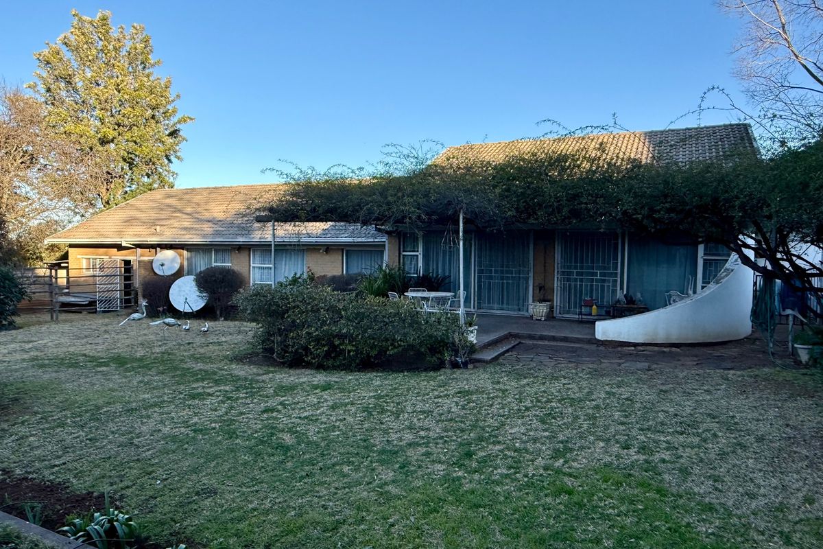 Rear view of the house featuring a brick facade, tiled roof, paved patio area, and access via sliding glass doors with security gates.