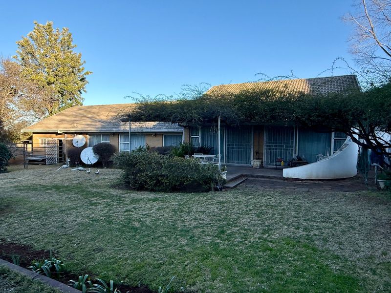 Rear view of the house featuring a brick facade, tiled roof, paved patio area, and access via sliding glass doors with security gates.