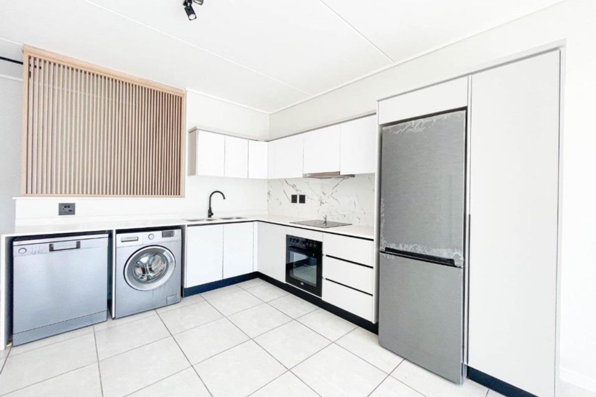 Modern, well-appointed kitchen featuring sleek white cabinetry, marble-look splashback, integrated appliances, and clean tiled flooring in a bright, contemporary space.