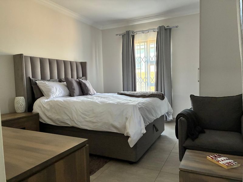 A well-maintained bedroom featuring neutral tiled flooring, a built-in wardrobe, and a security gate on the window for added peace of mind.