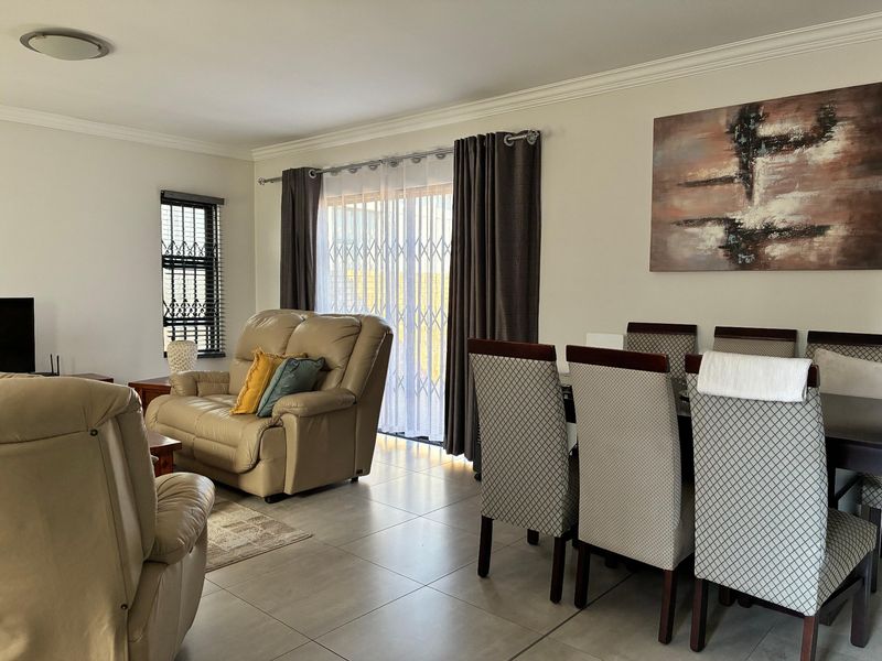 Spacious open-plan living and dining area featuring neutral tiled flooring, coving, and large sliding doors providing access to the outdoor space.