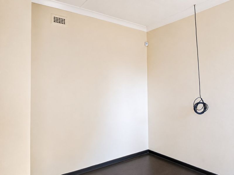 An empty room featuring neutral wall paint, dark flooring, and coving, with exposed electrical wiring hanging from the ceiling.