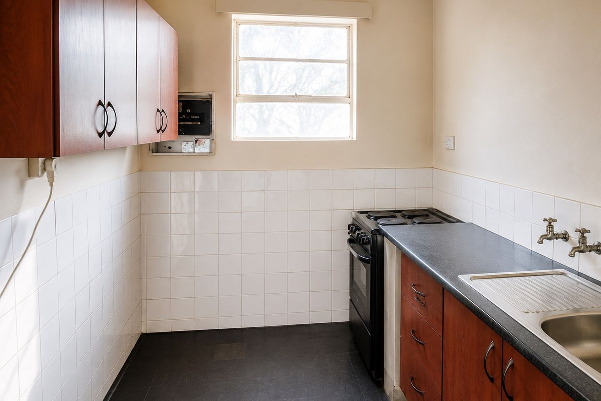 A functional kitchen featuring built-in cabinetry, a stainless steel sink, tiled backsplash, and a freestanding stove, offering a clean and practical workspace.