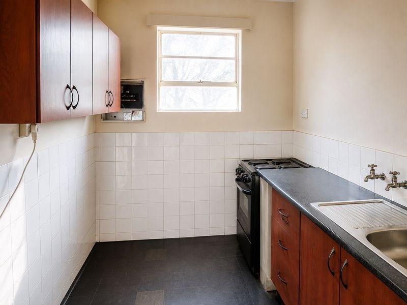 A functional kitchen featuring built-in cabinetry, a stainless steel sink, tiled backsplash, and a freestanding stove, offering a clean and practical workspace.