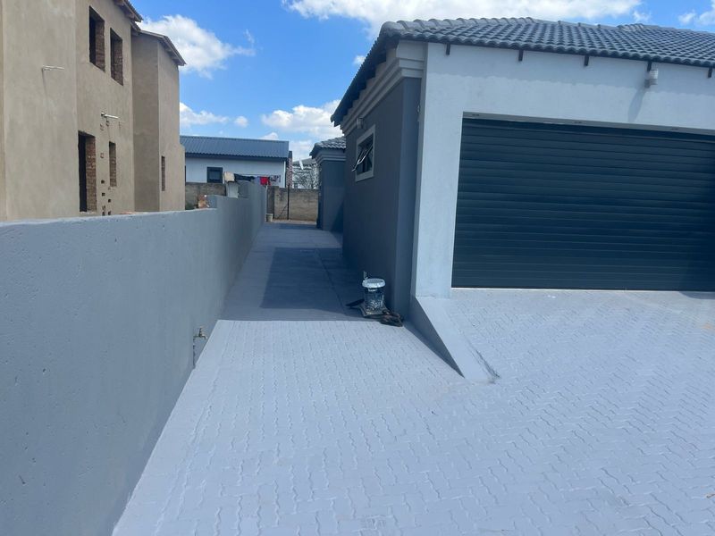 A view of the paved driveway leading to a garage, featuring a boundary wall and exterior access point.