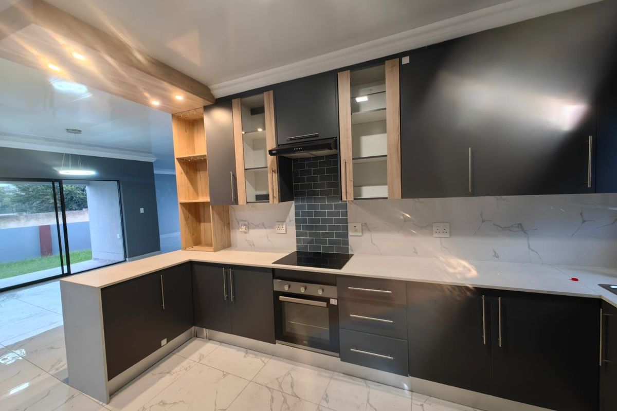 Modern kitchen featuring dark cabinetry, stone countertops, integrated appliances, subway tile backsplash, and marble-look floor tiles with an open-plan layout.