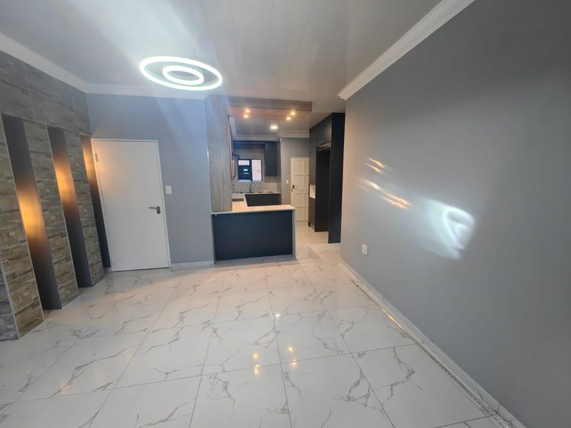 Modern open-plan living area featuring polished marble-look floor tiles, a stone-clad feature wall, and a sleek, contemporary kitchen with integrated cabinetry.
