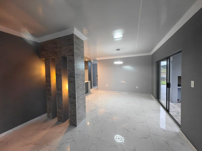 Spacious open-plan living area featuring modern marble-look floor tiles, a striking stone-clad feature pillar, and large sliding doors leading to the patio.