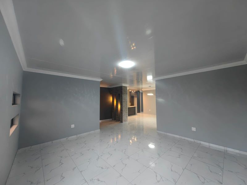 Spacious open-plan living area featuring high-gloss ceilings, marble-look floor tiles, and a decorative stone-clad pillar leading to a built-in bar area.