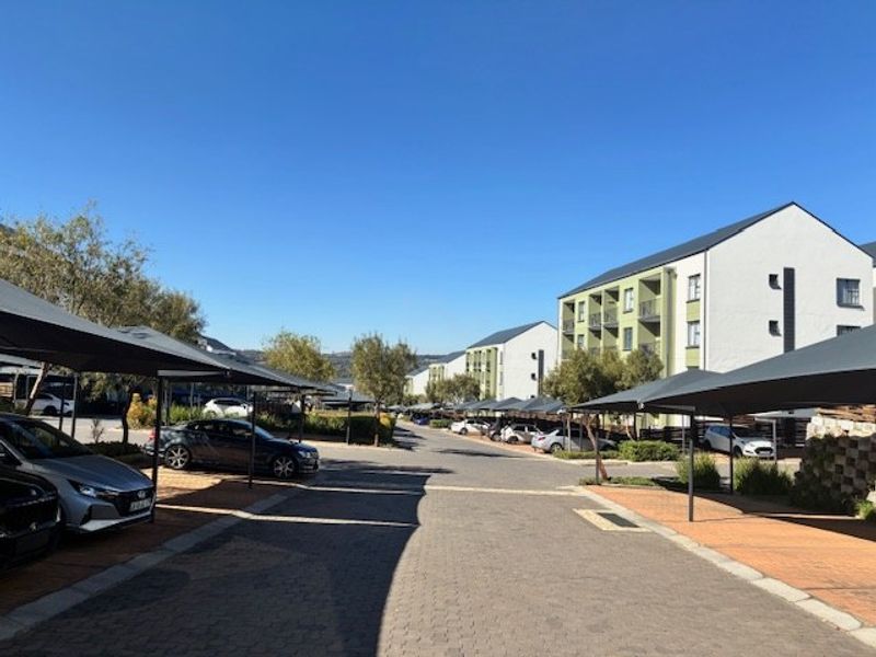 View of the apartment complex exterior featuring paved driveways, covered parking bays, and well-maintained multi-story residential buildings.