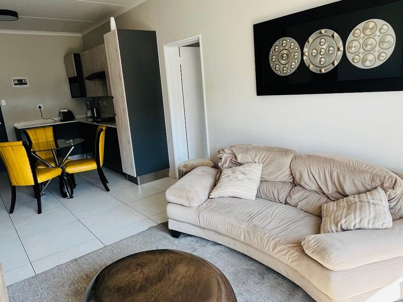 Open-plan living area featuring tiled flooring and a compact kitchen with modern cabinetry, creating a functional and connected living space.