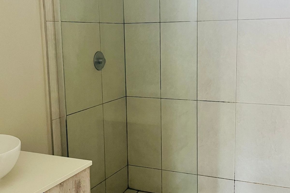 Modern bathroom featuring a walk-in shower with glass screen, rain shower head, and a contemporary vanity cabinet with basin.
