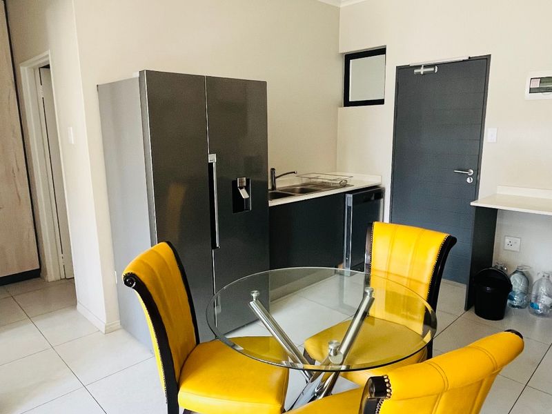 Open plan kitchen and dining area featuring tiled flooring, modern cabinetry, and a functional layout suitable for compact apartment living.