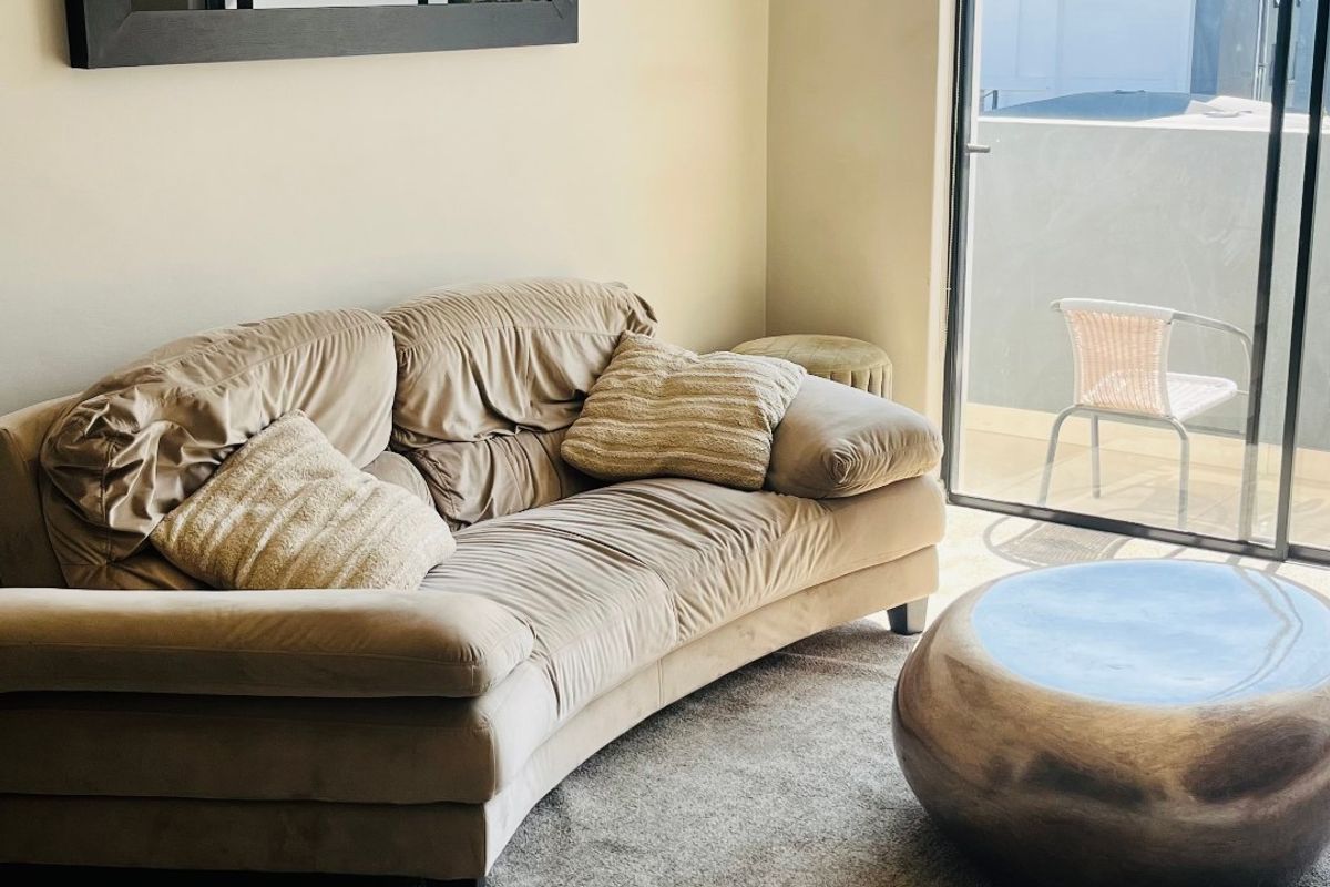 A living room area featuring tiled flooring and a large sliding glass door providing access to an outdoor balcony space.