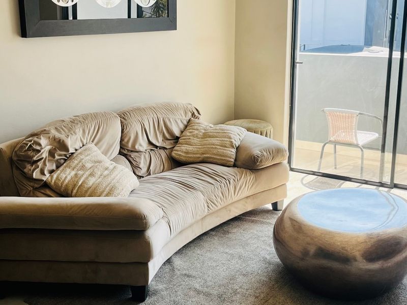 A living room area featuring tiled flooring and a large sliding glass door providing access to an outdoor balcony space.