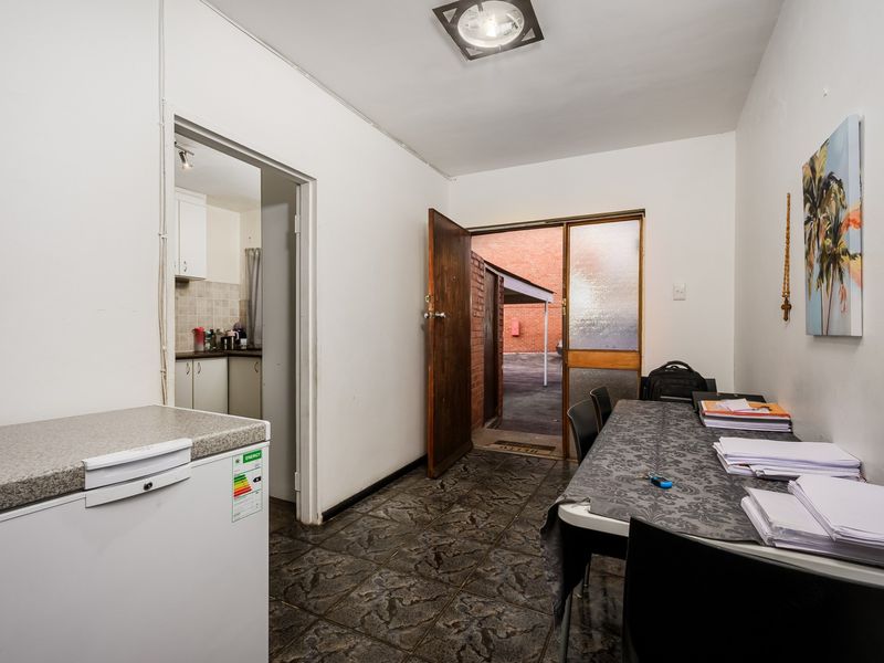 An entry area featuring tiled flooring and direct access to the exterior, with a view through to the adjacent kitchen space.