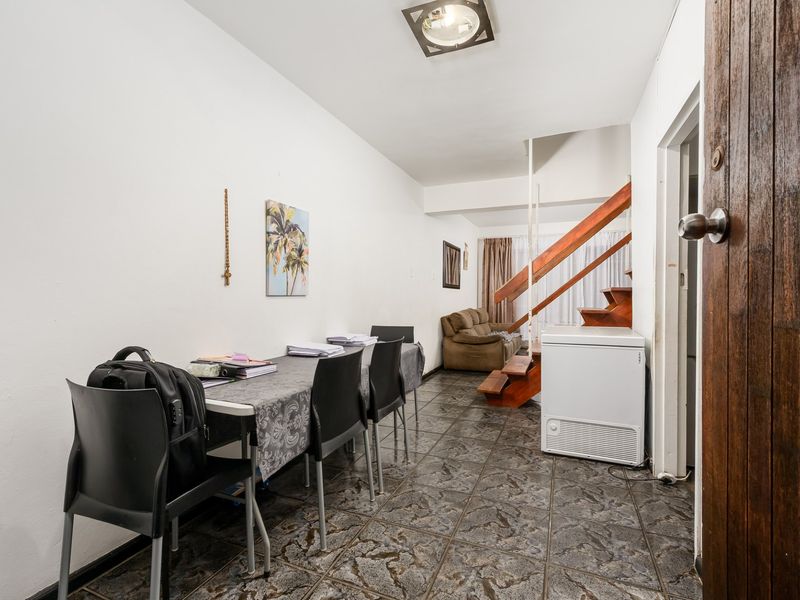 Open plan living area featuring tiled flooring and a wooden staircase leading to the upper level.