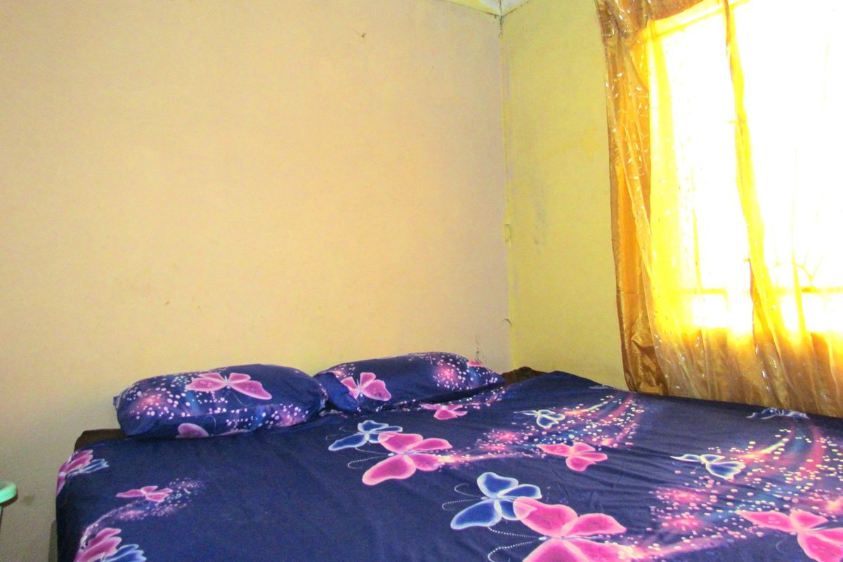 A bedroom featuring plain walls and a window with curtains, requiring cosmetic updates to improve the overall finish and condition of the space.