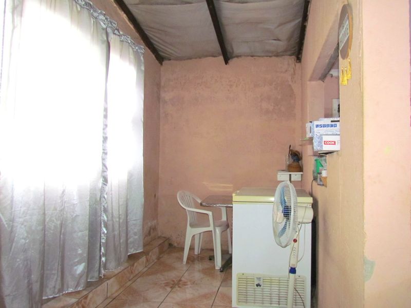 A small utility space featuring tiled flooring and an exposed beam ceiling, currently showing signs of wear and requiring cosmetic maintenance.