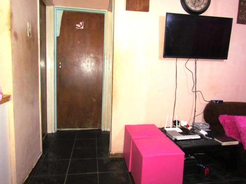 A living area featuring dark tiled flooring and a standard internal door, showing signs of wear and requiring cosmetic updates.