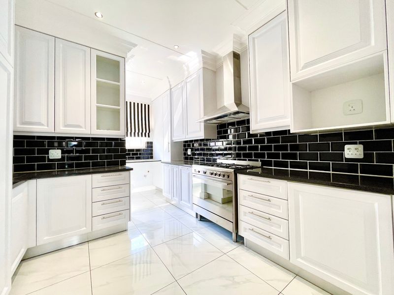 Modern kitchen featuring white shaker cabinetry, black subway tile backsplash, granite countertops, and a stainless steel gas stove with extractor fan.