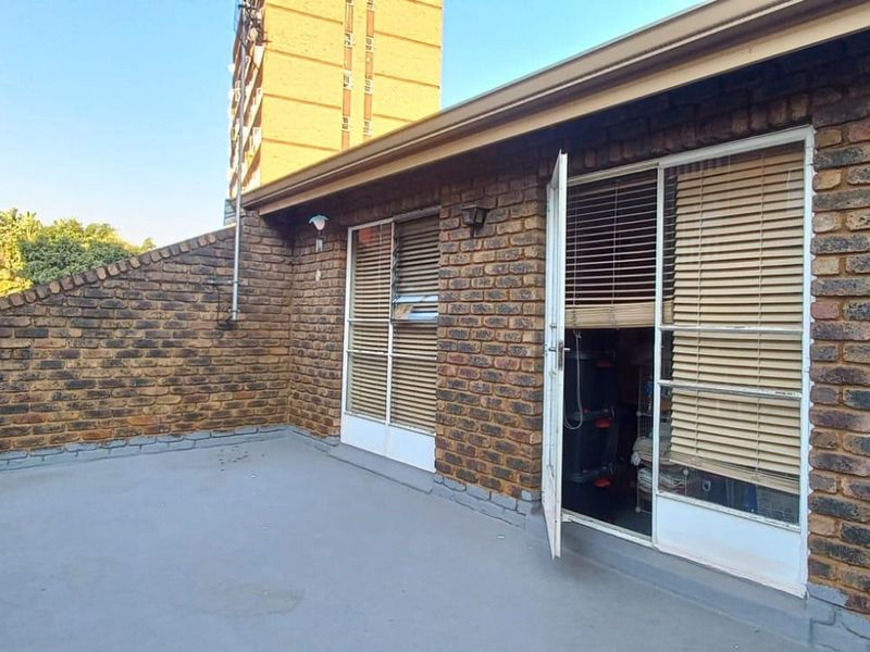 An open-air patio featuring exposed brick walls, a utility sink, and direct access to the interior through sliding doors.