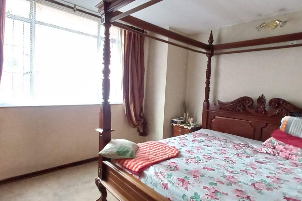 A bedroom featuring a large window with security bars, providing natural light to the space.