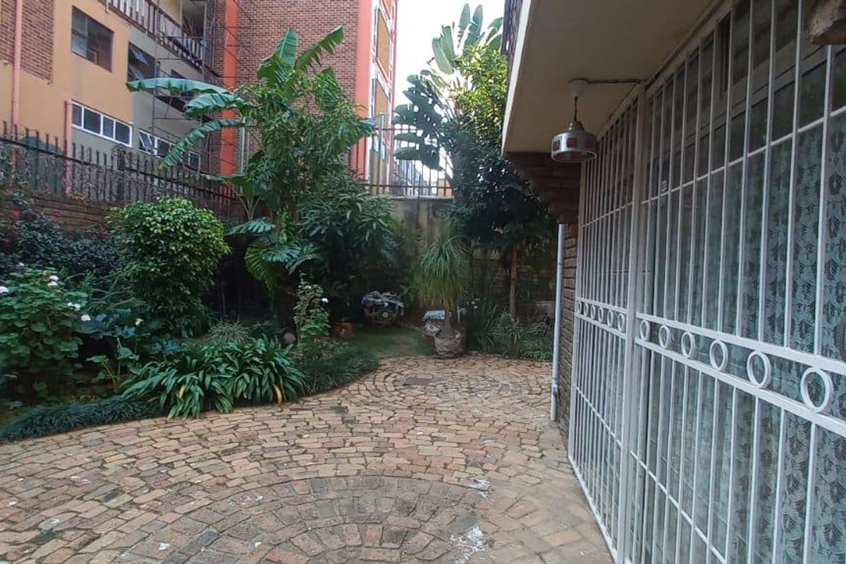 A private rear courtyard featuring brick paving, established garden landscaping, and a secure gated entrance to the townhouse.