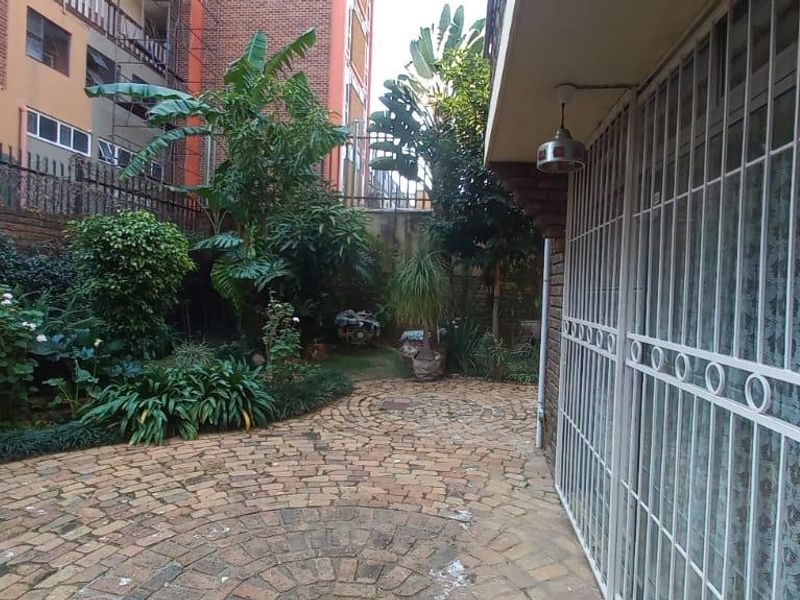 A private rear courtyard featuring brick paving, established garden landscaping, and a secure gated entrance to the townhouse.