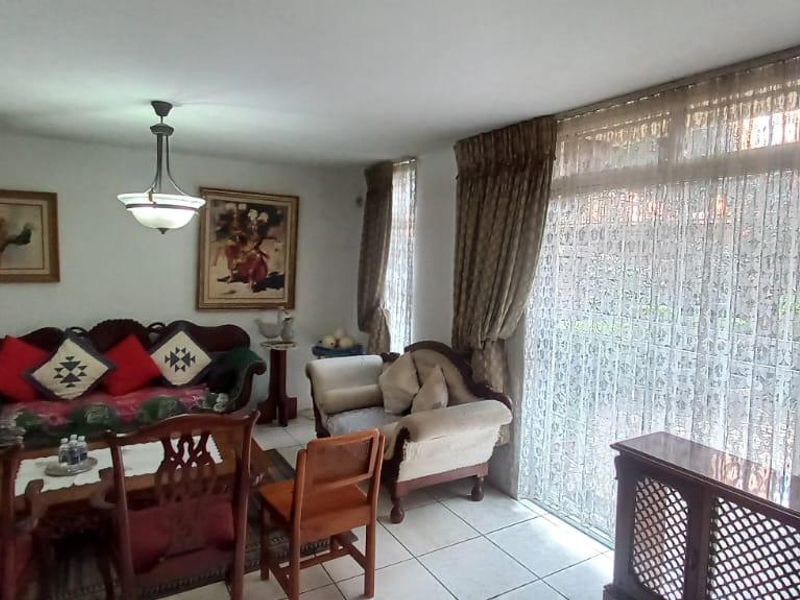 A living room featuring tiled flooring and a large sliding glass door that provides natural light and access to the exterior.