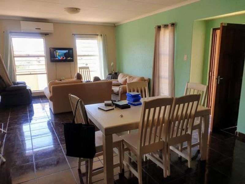 Open-plan living and dining area featuring tiled flooring and a wall-mounted air conditioning unit.