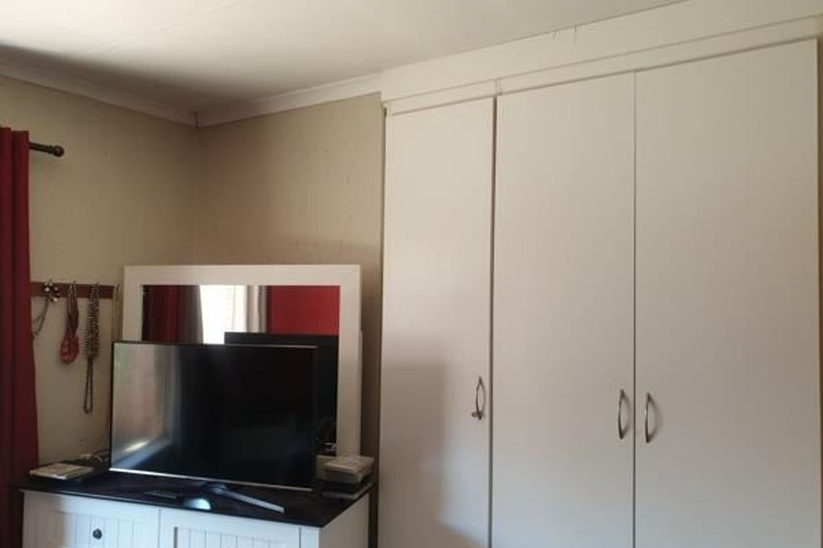 A bedroom featuring built-in cupboards with white doors and decorative ceiling coving.
