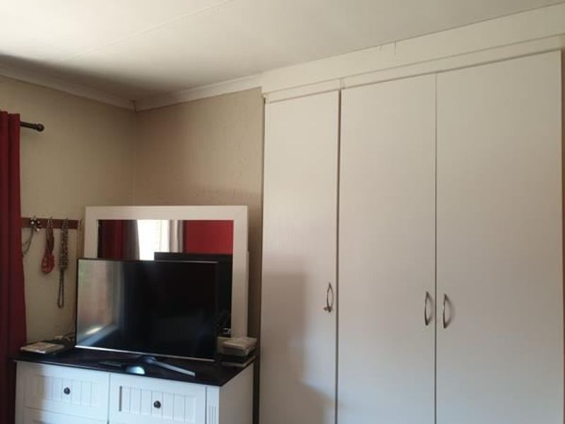 A bedroom featuring built-in cupboards with white doors and decorative ceiling coving.