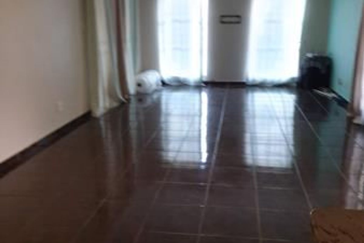 Spacious, empty living area featuring dark tiled flooring, an air conditioning unit, and large sliding glass doors providing natural light.