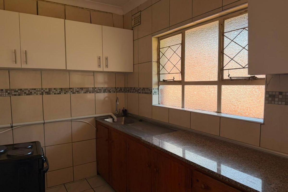 A functional kitchen featuring granite countertops, built-in cabinetry, and tiled finishes, offering potential for modernization and cosmetic updates.