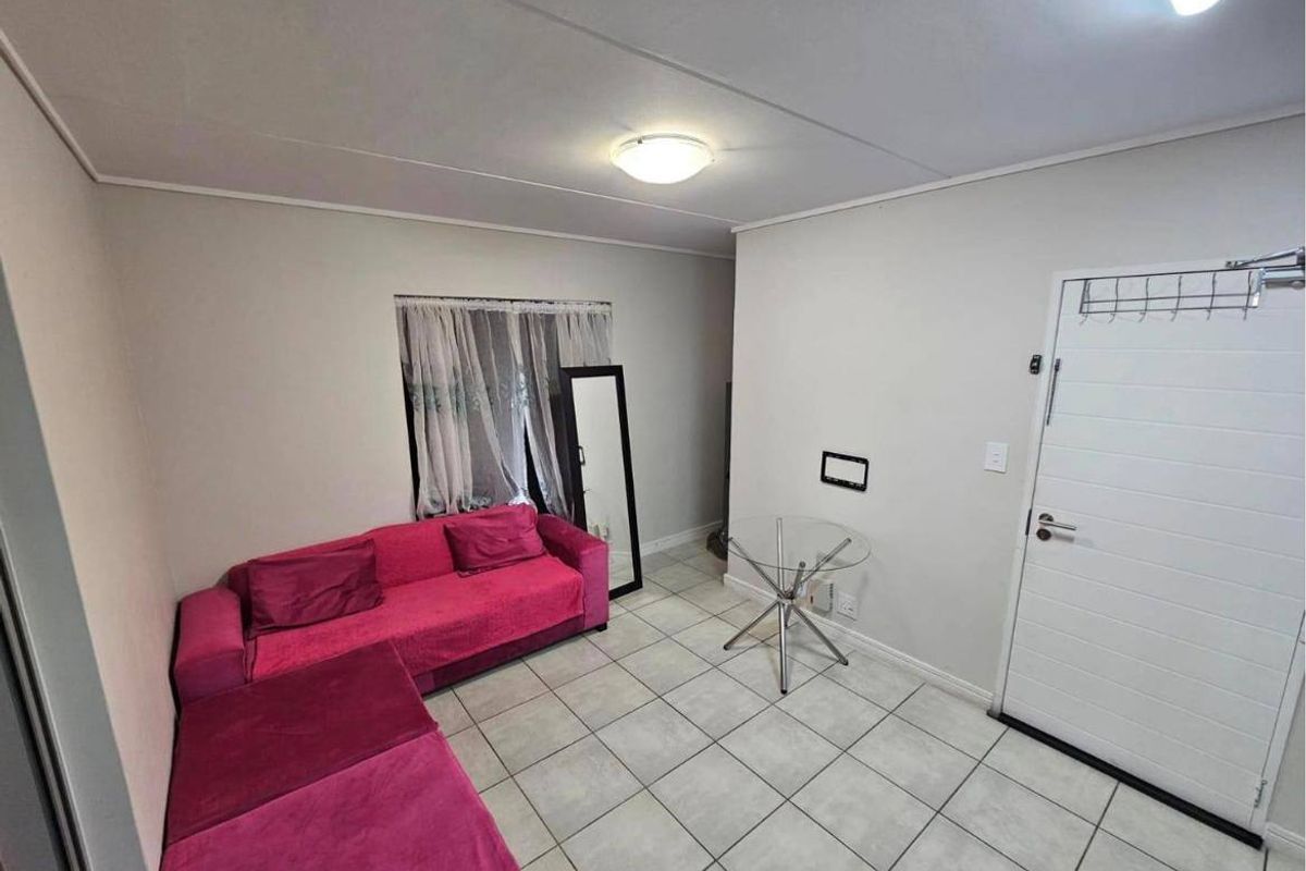 A simple living area featuring neutral wall finishes, tiled flooring, and a standard panel door entrance.