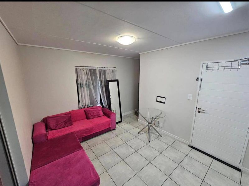 A simple living area featuring neutral wall finishes, tiled flooring, and a standard panel door entrance.