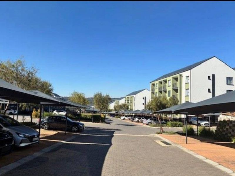 View of the apartment complex entrance featuring paved driveways and covered parking bays for residents.