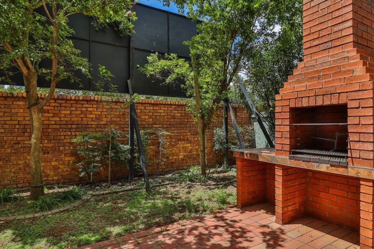 Rear garden area featuring a built-in brick fireplace and paved patio, unfortunately dominated by a large adjacent billboard structure.