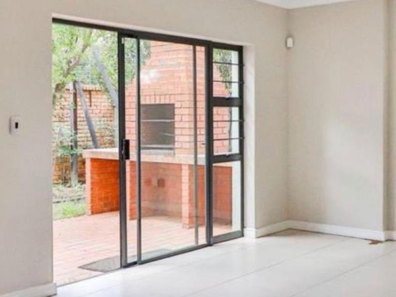 Bright living area featuring large sliding glass doors that open onto a private patio with a built-in brick braai.