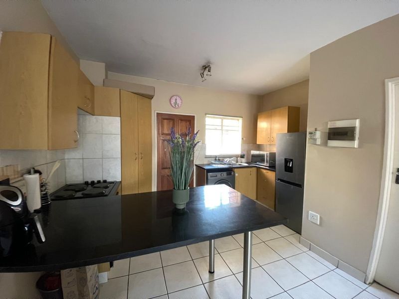 Functional kitchen featuring built-in wooden cabinetry, black granite countertops, a hob, and tiled flooring with a breakfast nook area.
